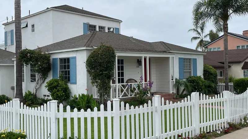 White home with blue shutters and a picket fence after painting