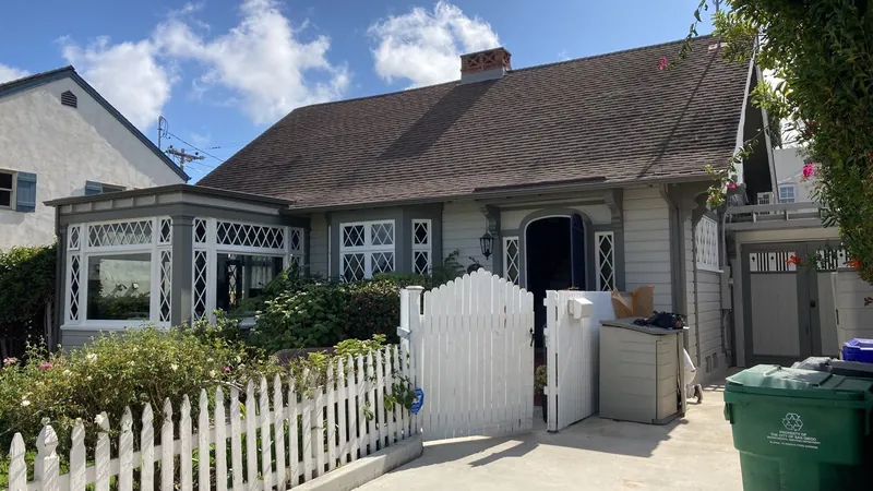 Gray cottage with white trim and picket fence after painting